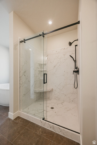 5910 Canyon Rim Road, Unit 619 Lehi, UT 84048 - Photo 33 of 52 Walk-in shower with clear glass barn door style enclosure, white marble-look tile, built-in bench, and black fixtures