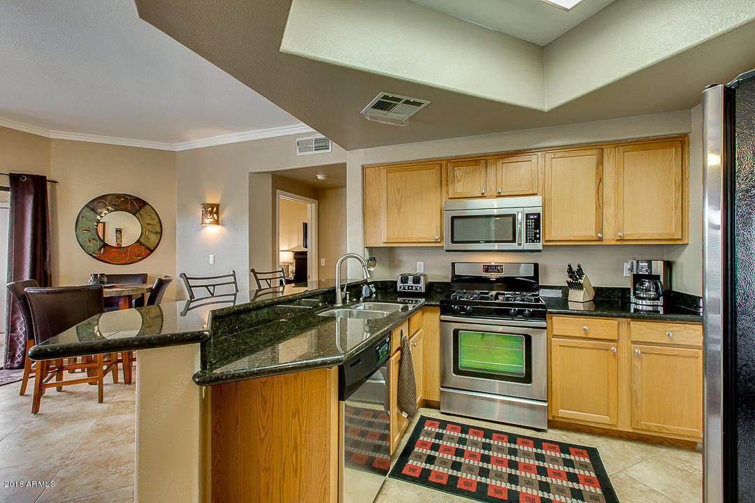10030 West Indian School Road, Unit 269 Phoenix, AZ 85037 - Photo 13 of 34 a kitchen with granite countertop a stove a sink dishwasher a dining table and chair with wooden floor