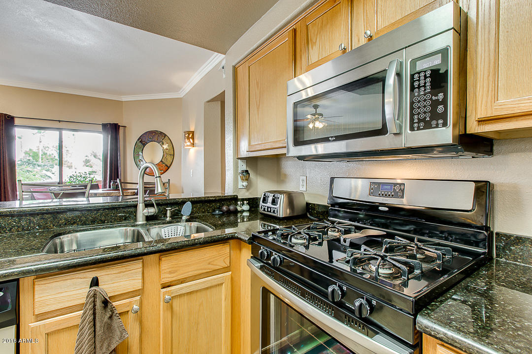 10030 West Indian School Road, Unit 269 Phoenix, AZ 85037 - Photo 15 of 34 a kitchen with stainless steel appliances granite countertop a stove and a microwave