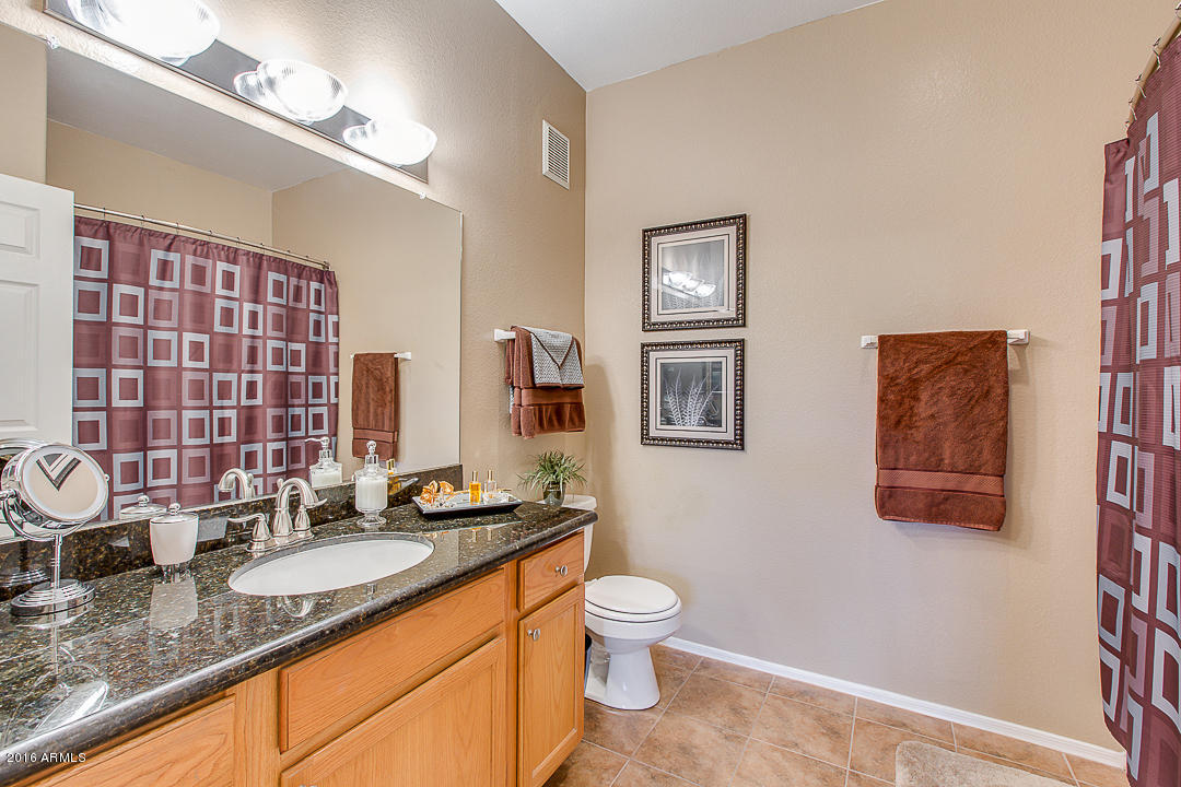 10030 West Indian School Road, Unit 269 Phoenix, AZ 85037 - Photo 21 of 34 a bathroom with a granite countertop toilet sink and mirror