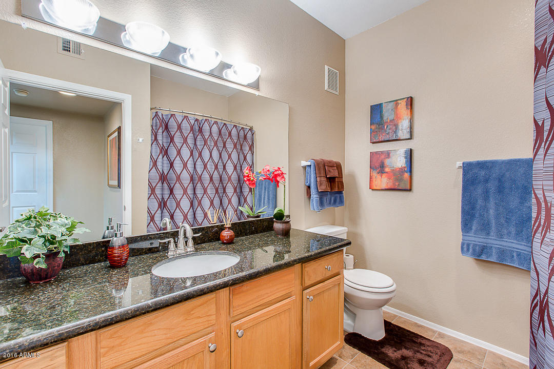 10030 West Indian School Road, Unit 269 Phoenix, AZ 85037 - Photo 23 of 34 a bathroom with a granite countertop sink mirror vanity and toilet