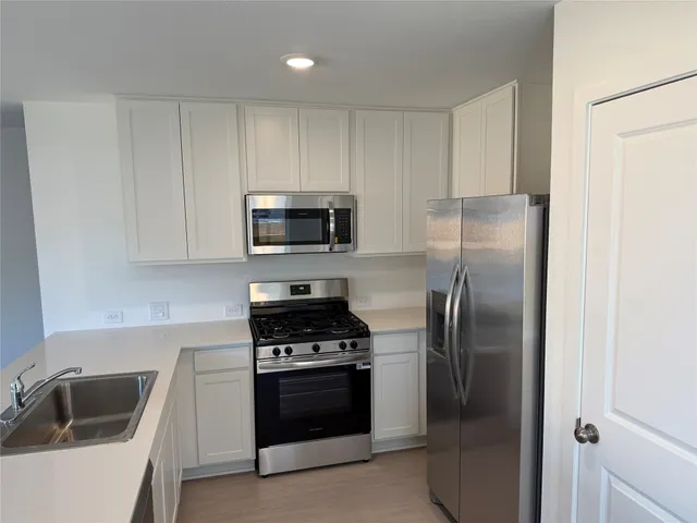 a kitchen with refrigerator a microwave a sink and cabinets