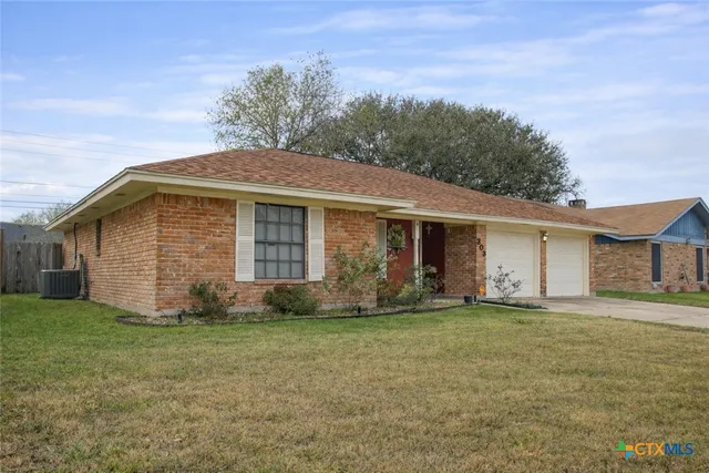 a front view of house with yard and trees in the background