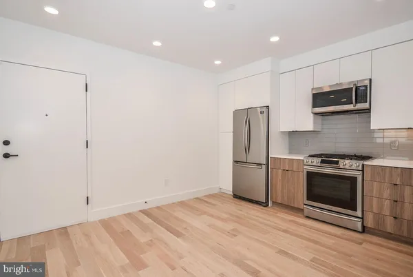a kitchen with stainless steel appliances granite countertop a refrigerator and a stove top oven