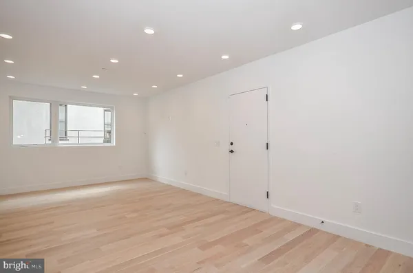 an empty room with wooden floor and window