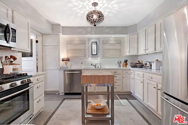 a kitchen with granite countertop a sink cabinets and stainless steel appliances