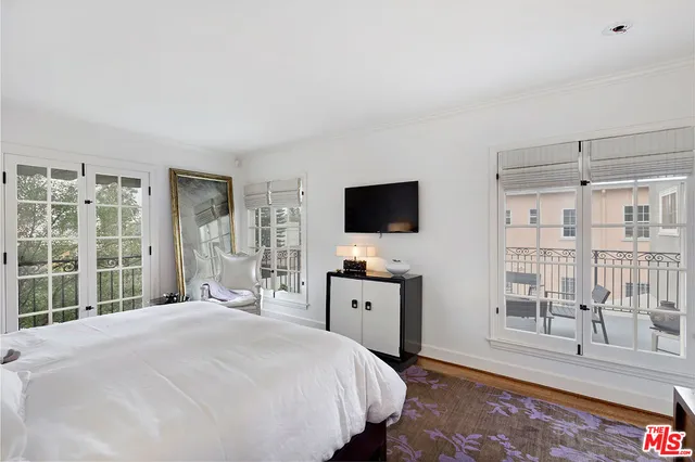 a bedroom with a large bed and a flat tv screen on dresser