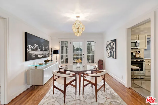 a dining room with wooden floor a chandelier a wooden table and chairs