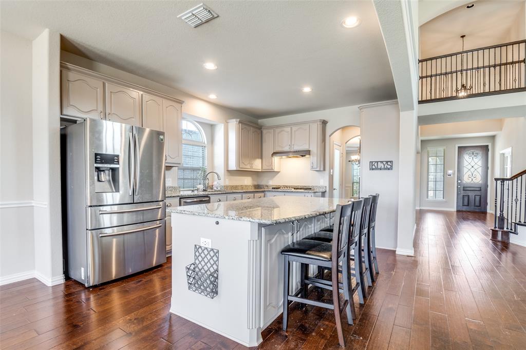679 Princeton Way Rockwall, TX 75087 - Photo 5 of 25 a kitchen with stainless steel appliances granite countertop a refrigerator a stove a sink dishwasher and a dining table with wooden floor