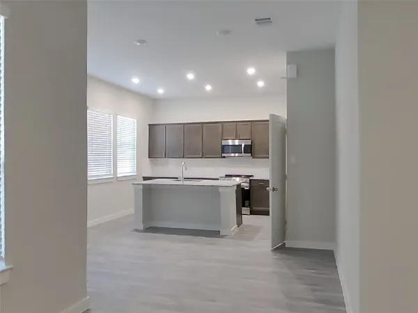 a large white kitchen with a sink a microwave and cabinets