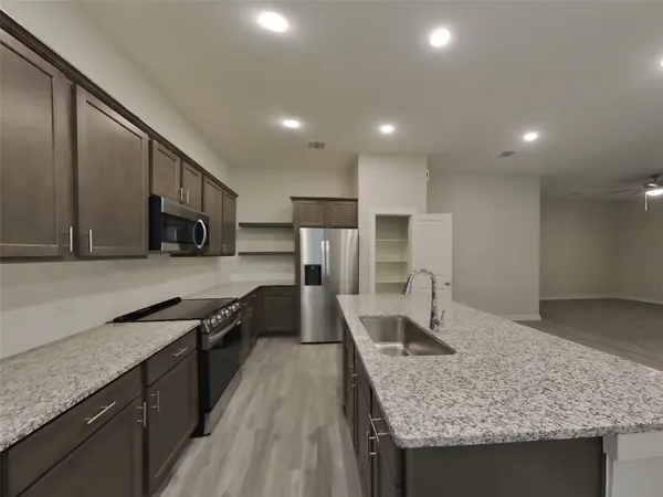 a large kitchen with stainless steel appliances granite countertop a sink stove and refrigerator