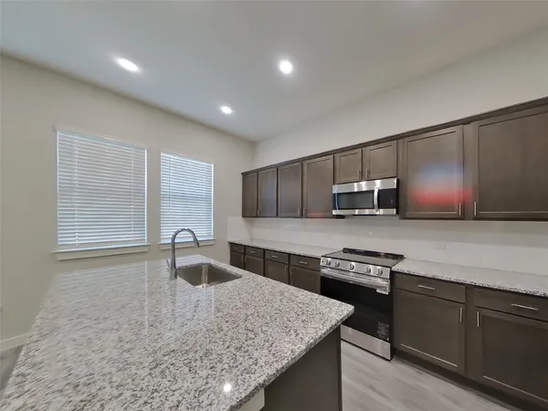 a kitchen with stainless steel appliances granite countertop a sink stove and microwave