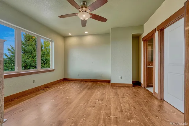 an empty room with a ceiling fan and a large window