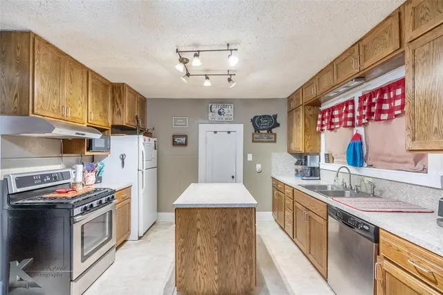 a kitchen with stainless steel appliances granite countertop a sink stove and refrigerator