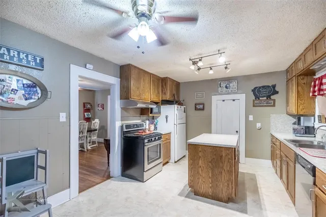 a large kitchen with stainless steel appliances granite countertop a refrigerator a stove oven a sink dishwasher and white cabinets with wooden floor