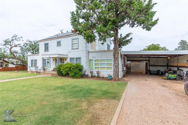 a view of a house with backyard and a tree