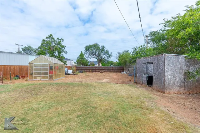 a view of a house with a yard and large tree