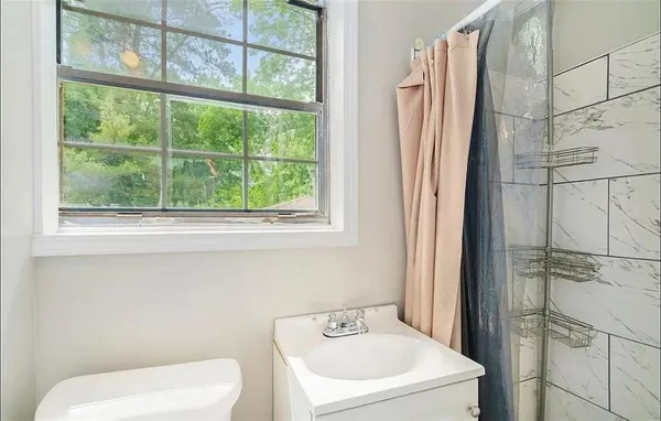 a bathroom with a toilet sink and next to a window
