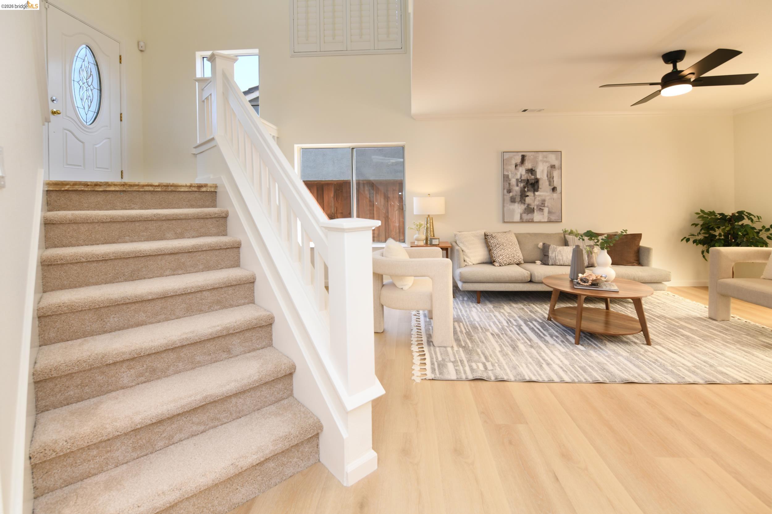512 Burdick Drive Bay Point, CA 94565 - Photo 21 of 50 Entryway featuring a carpeted staircase with white balusters, wood-finish flooring, a decorative glass-paneled entry door, and a living area with a ceiling fan