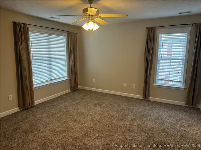 an empty room with windows and fan