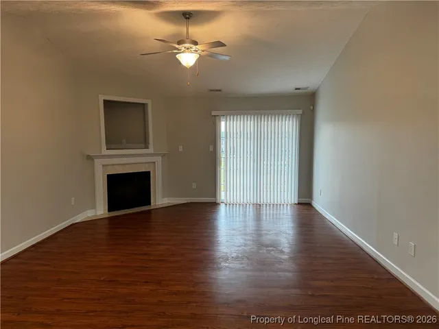 a view of an empty room with wooden floor and a fireplace