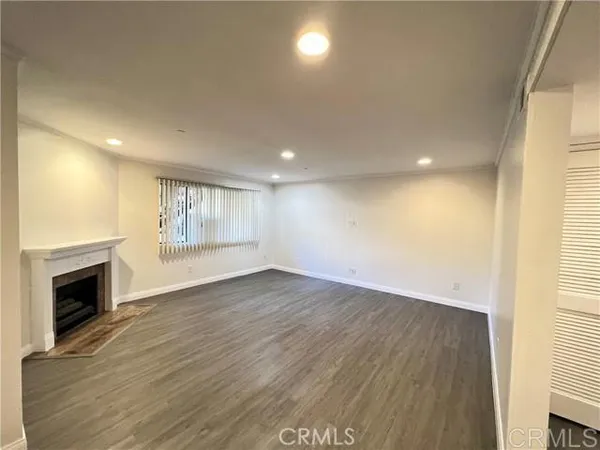 an empty room with wooden floor fireplace and windows