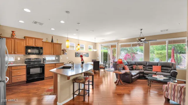 a kitchen with stainless steel appliances granite countertop a stove top oven a sink dishwasher a dining table and chairs with wooden floor