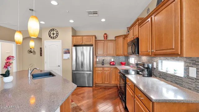 a kitchen with stainless steel appliances granite countertop a sink refrigerator and cabinets