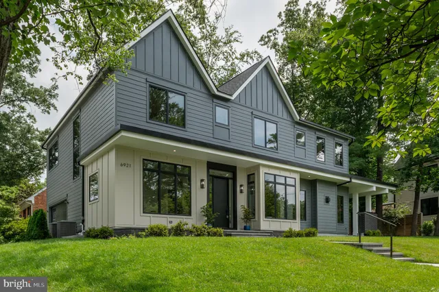 a view of a white house next to a yard with large trees
