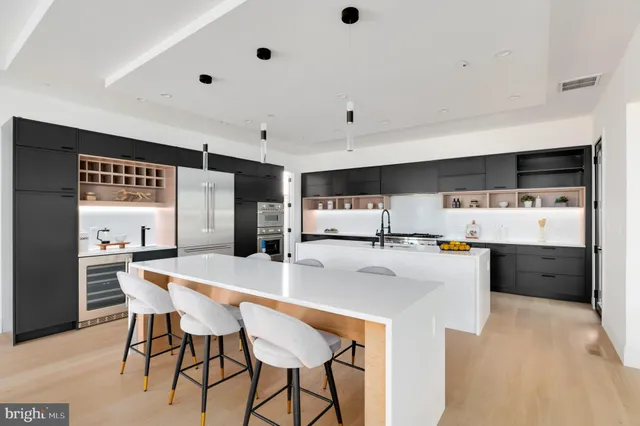 a kitchen with stainless steel appliances a white table chairs and a refrigerator