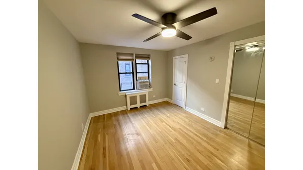 a view of a hallway with wooden floor and a ceiling fan