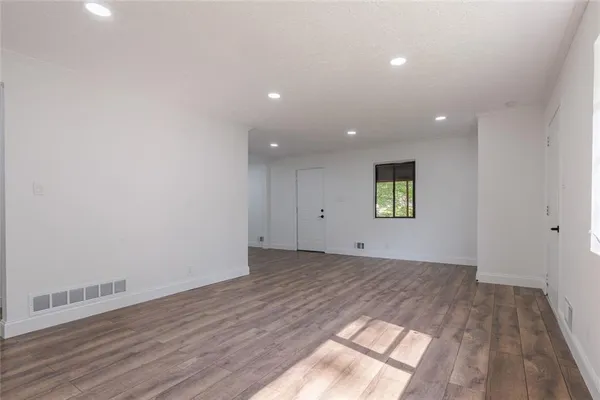 an empty room with wooden floor and windows