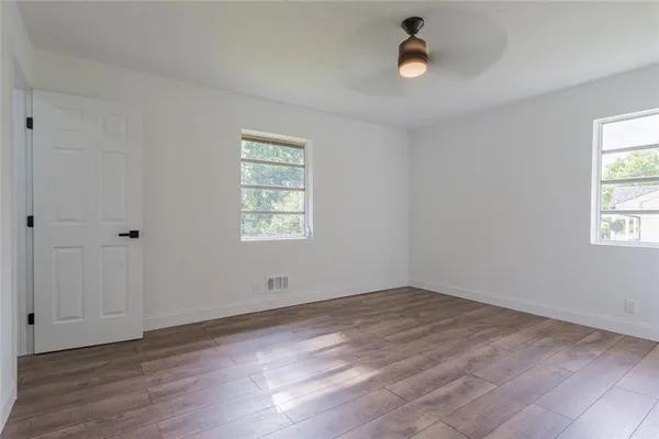 an empty room with wooden floor and windows