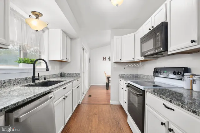a kitchen with granite countertop a sink a stove and cabinets