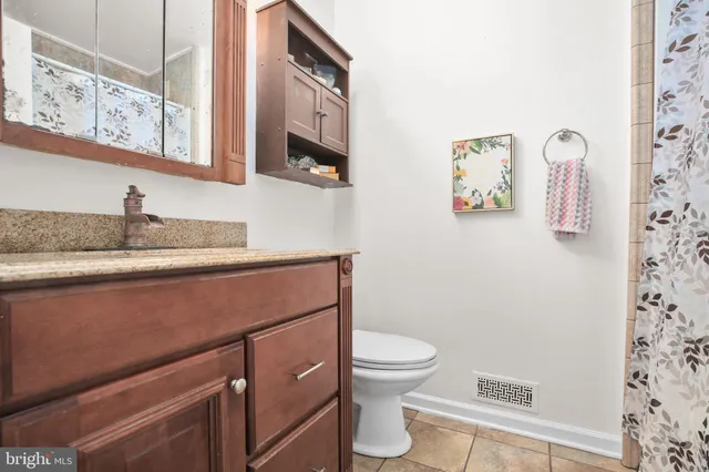 a bathroom with a granite countertop sink and a toilet