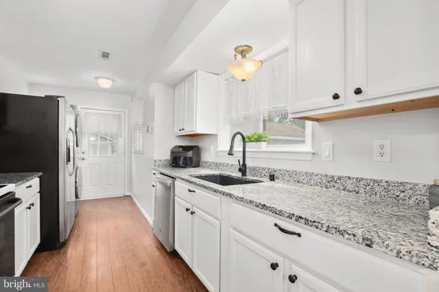 a kitchen with granite countertop a sink a counter space appliances and cabinets