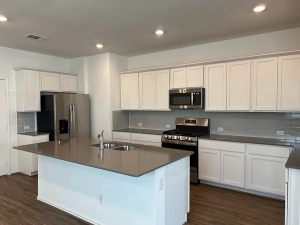 a large white kitchen with lots of counter space a sink dishwasher and a refrigerator