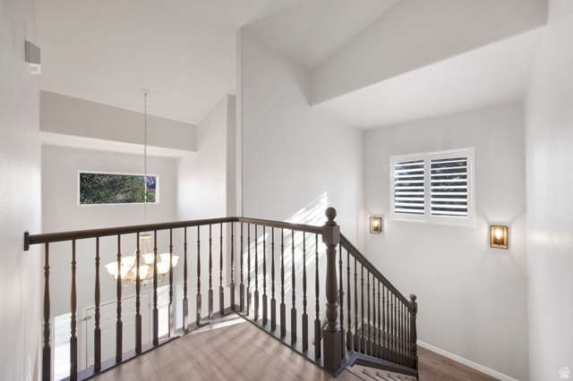 1440 West 100 South Virgin, UT 84779 - Photo 17 of 45 Stairwell featuring a dark wood newel post and balusters, wood-finish flooring, two wall-mounted sconces, and a window with plantation shutters