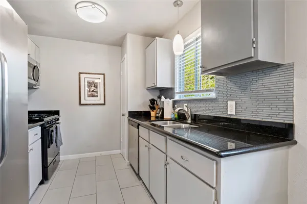a kitchen with granite countertop a stove sink and cabinets