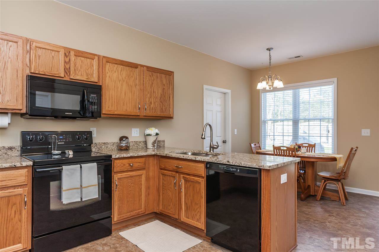 5421 Neuse Forest Road Raleigh, NC 27616 - Photo 7 of 21 a kitchen with stainless steel appliances granite countertop a sink a stove a microwave and wooden cabinets
