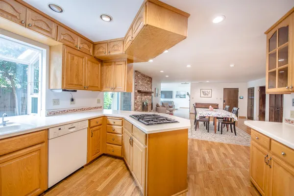 a kitchen with stainless steel appliances granite countertop a refrigerator a sink dishwasher a stove and white countertops with wooden floor