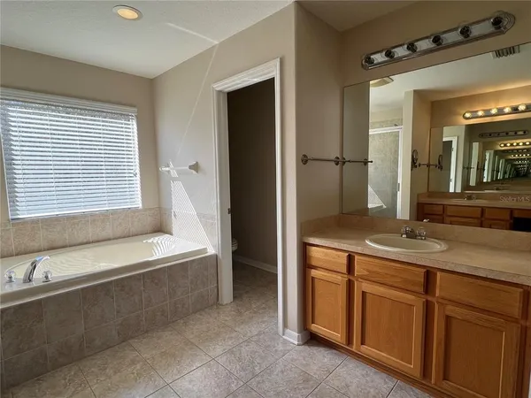 a spacious bathroom with a granite countertop sink a mirror and a bathtub