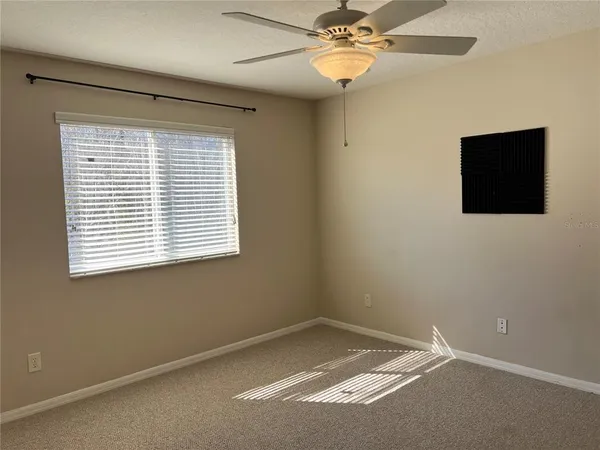en empty room with windows and ceiling fan