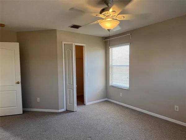 an empty room with a window and a ceiling fan
