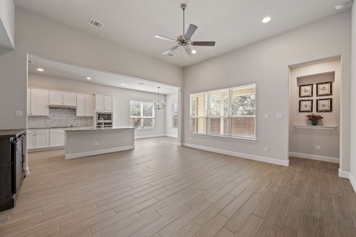 1601 Highland Ridge Road Georgetown, TX 78628 - Photo 5 of 37 a view of an empty room with wooden floor and a kitchen