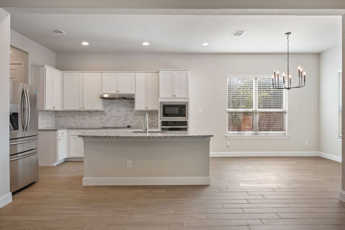 1601 Highland Ridge Road Georgetown, TX 78628 - Photo 7 of 37 a kitchen with stainless steel appliances granite countertop a stove a sink and white cabinets