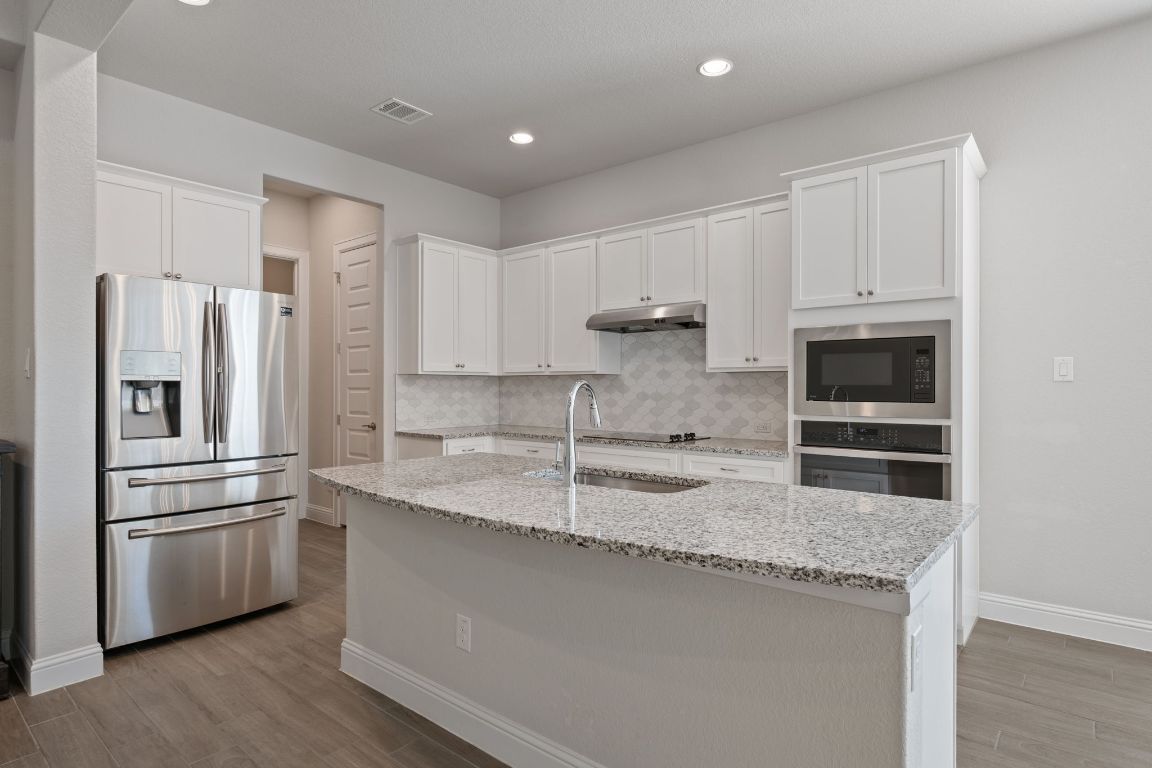 1601 Highland Ridge Road Georgetown, TX 78628 - Photo 8 of 37 a kitchen with granite countertop a refrigerator and a sink
