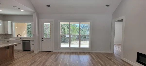 a view of a kitchen & microwave and an empty room with wooden floor