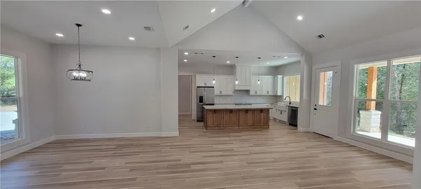 a large kitchen with a large counter top space a sink stainless steel appliances and a window