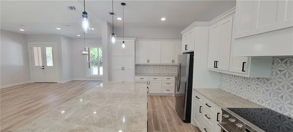 a kitchen with kitchen island white cabinets and stainless steel appliances